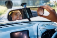 Preview: A woman adjusting a rear view mirror while driving car