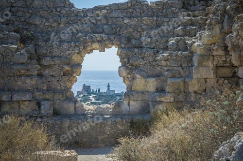 Preview: View of lighthouse through hole in stone wall, Cagliari, Masua, Sardinia, Italy