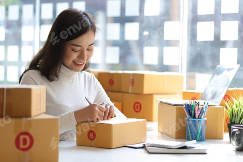 Preview: Freelance Asian woman small business entrepreneur SME working with box at home.