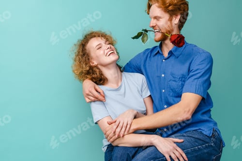 Preview: Young happy redhead couple with rose making fun at camera