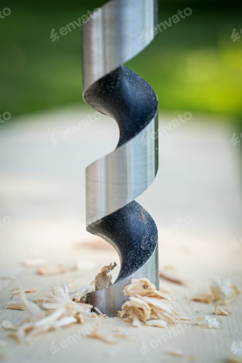 Preview: Vertical shot of a metal drill bit making a hole in the wood