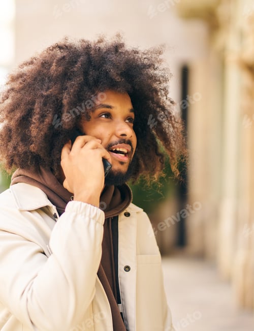 Preview: Young man with curly afro hair on the street talking on the cell phone