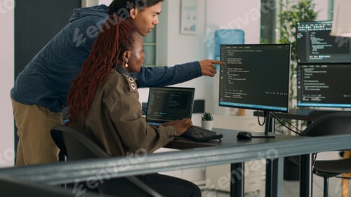 Preview: Two software coders analyzing source code on computer and laptop screen