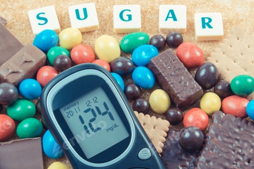 Preview: Glucose meter for checking sugar level and heap of sweets containing a lot of sugar