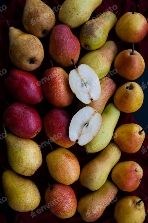 Preview: Yellow and red juicy fragrant pears lie on a cherry tablecloth on a black wooden background.