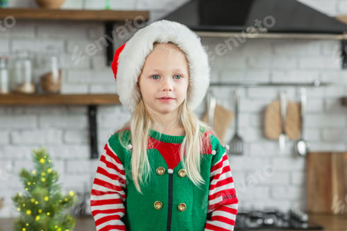 Preview: Girl in santa claus hat smiling and posing in cozy kitchen