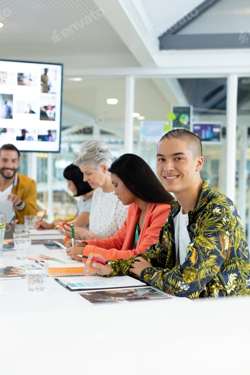 Preview: Mixed race businessman looking at the camera while diverse business people discussing in the meeting