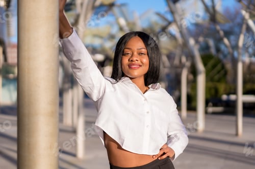 Preview: Young african woman in white clothes in the city at sunset doing a fashion posing smiling looking
