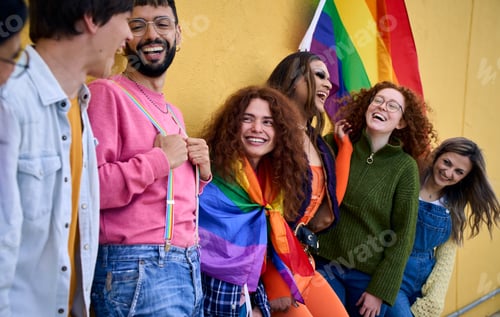 Preview: Portrait laughing young group of friends standing on wall yellow. LGBT community happy people.