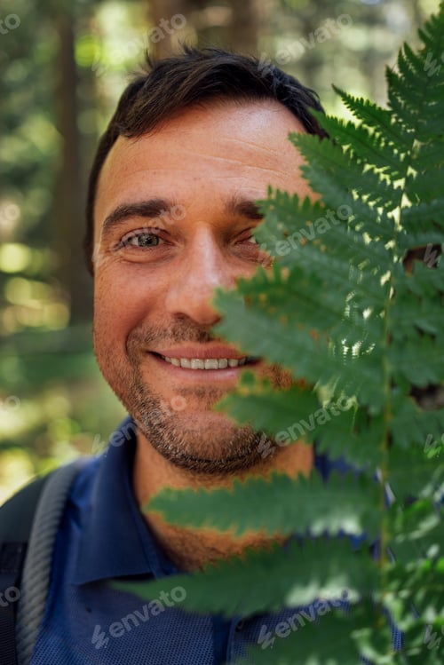 Preview: Close-up portrait of young happy man with fern in nature