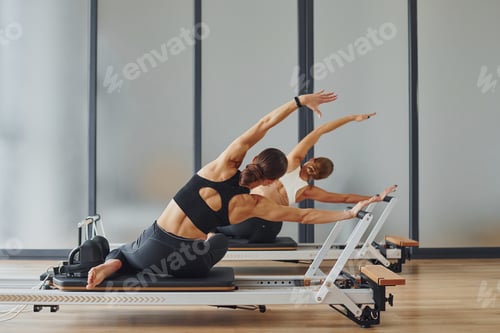 Preview: Two women in sportive wear and with slim bodies have fitness yoga day indoors together