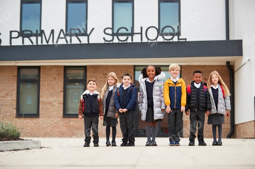 Preview: Primary school kids standing in front of their school looking to camera, full length, low angle