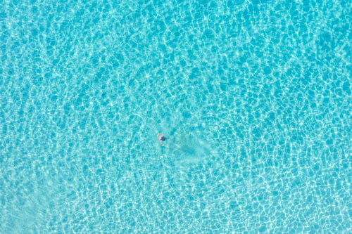 Preview: Man swim in transparent turquoise blue sea water aerial drone view. Summer sunny day, Greece