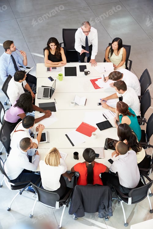 Preview: Businessman Addressing Meeting Around Boardroom Table