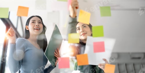 Preview: Two young creative woman planning on a glass board.
