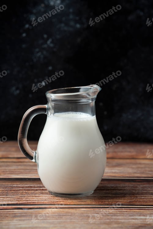 Preview: Glass jug of fresh milk on wooden table