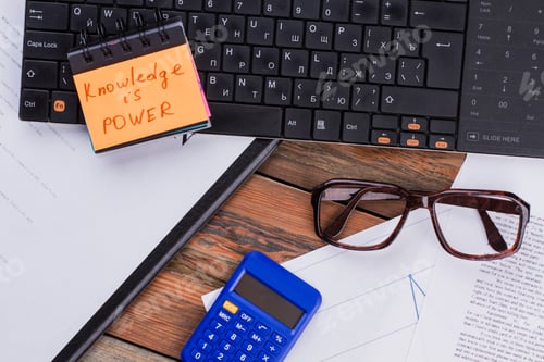 Preview: Top view of wooden desktop with keyboard glasses document and calculator.