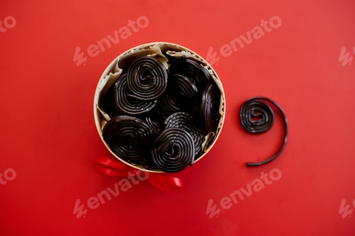 Preview: Female hand take tasty black liquorice candies from present box
