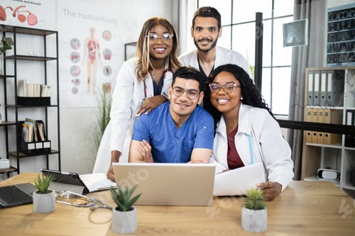 Preview: Close up of four international doctors with gadgets at modern office in clinic