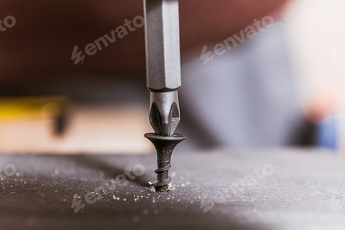 Preview: Drill Bit Driving Black Screw Into Wooden Surface