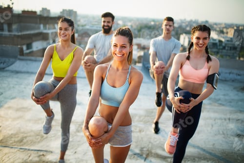 Preview: Group of happy fit friends exercising outdoor in city