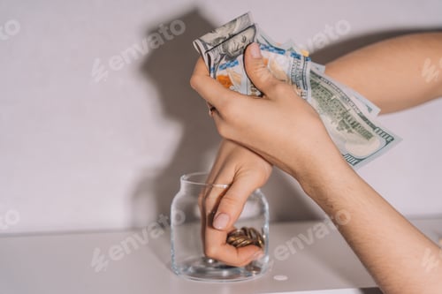 Preview: Hands take out dollar bills and coins from a glass jar