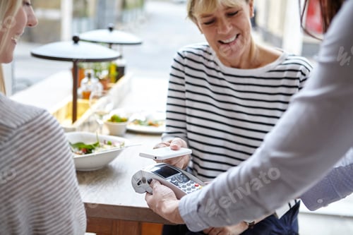 Preview: Woman using smartphone contactless payment at restaurant table, London, UK
