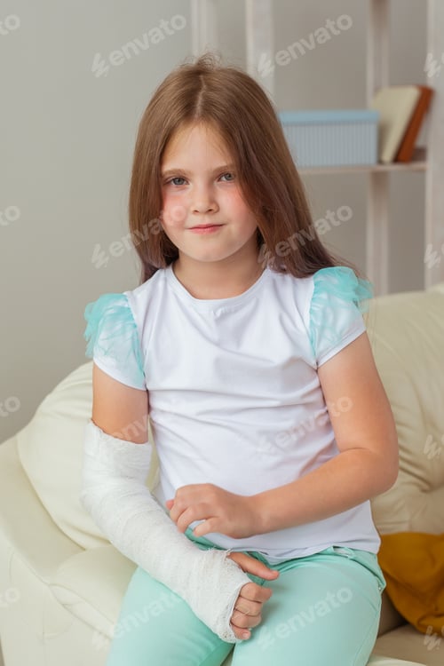 Preview: Child with a cast on a broken wrist or arm smiling and having fun on a couch. Positive attitude