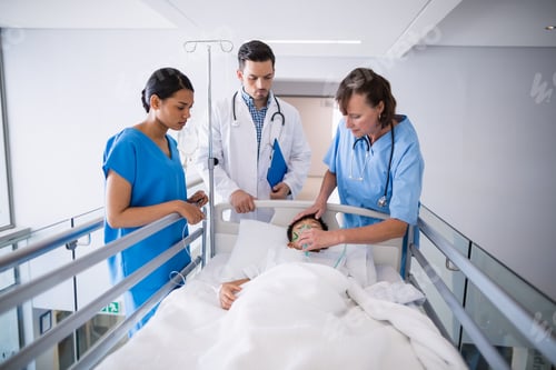 Preview: Doctors examining patient in corridor
