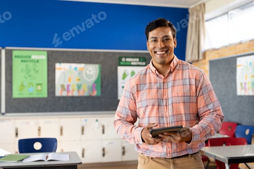 Visualização: Retrato de feliz professor birracial masculino com tablet em sala de aula na escola primária, espaço de cópia