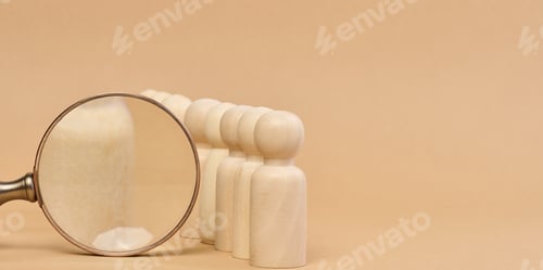Preview: Wooden figures of men stand on a beige background and a wooden magnifying glass. Recruitment concept