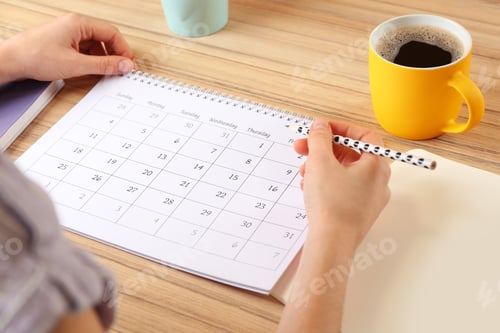 Preview: Woman with calendar at wooden table in office, closeup