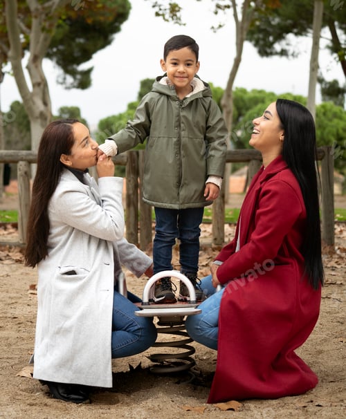 Preview: Portrait of happy lesbian family with their son spending time together in a park outdoors