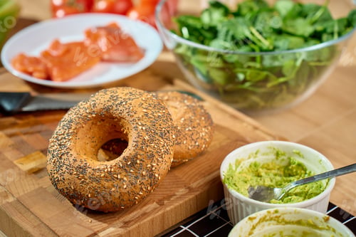 Preview: Bagels with mashed avocado spread and salmon ingredients on table