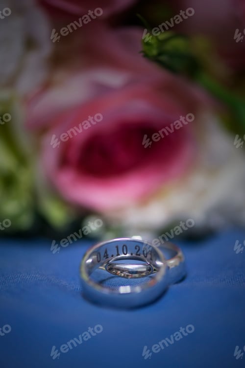 Preview: Wedding rings lie on a beautiful bouquet as bridal accessories