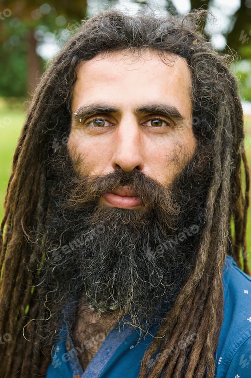 Preview: A man with long dreadlocks in a blue shirt.