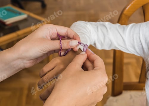 Preview: Mother tying a hand made bracelet to her daughter