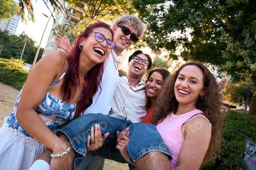 Preview: Cheerful students lifting their friend, laughing and having fun in a park