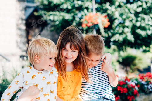 Preview: three children are sitting in an embrace, smiling, laughing, having fun
