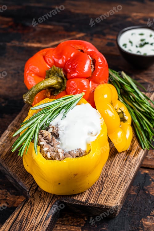 Preview: Roast bell pepper stuffed with beef meat, rice and vegetables on a wooden board.