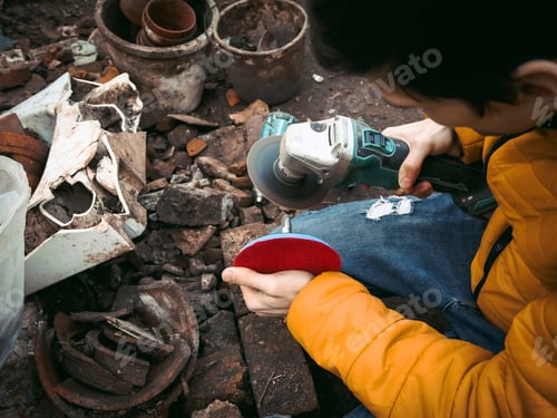 Preview: A young Caucasian male in a yellow jacket is holding a drill in his hands and polishing with a disc