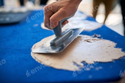 Preview: Man hand with trowel plastering a blue surface