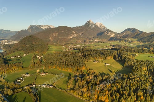 Preview: Aerial view of green meadows with villages and forest in austrian Alps mountains.