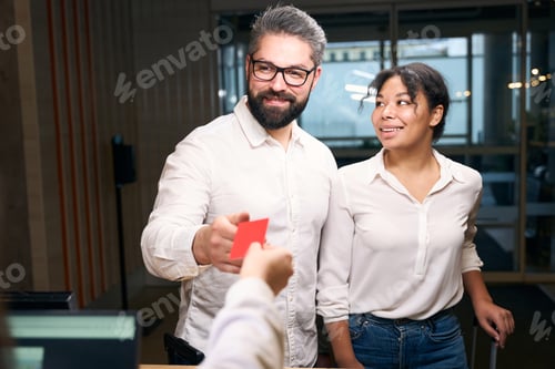 Preview: Happy couple getting keycard from front desk clerk
