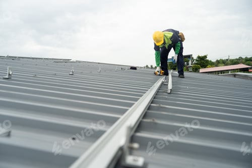 Preview: Men technicians mounting photovoltaic solar moduls on rooftop of warehouse.