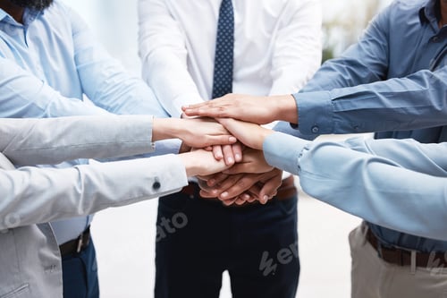 Preview: No funny business. Shot of a group of business people with their hands stacked.