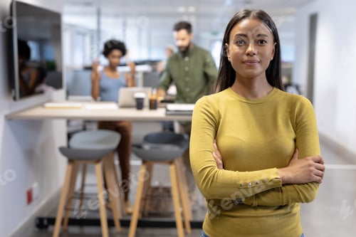 Preview: Portrait of confident young african american female advisor standing with arms crossed at workplace