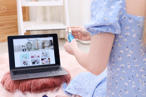 Preview: Blogger holding cosmetic product near laptop with fashion blog web site on floor indoors, closeup
