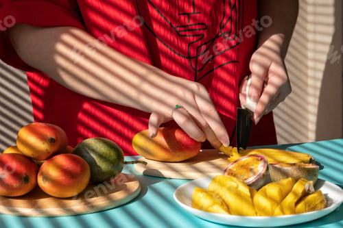 Preview: female hands cut mango and passion fruit, fruit breakfast