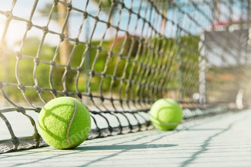 Preview: Tennis ball. Green tennis ball lies near net on tennis court on sunny day. Concept of healthy lifest